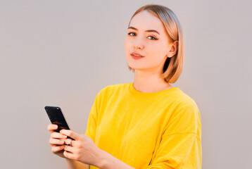 Portrait of a smiling casual woman holding smartphone over gray background