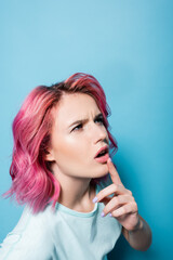 Obraz premium pensive young woman with pink hair on blue background