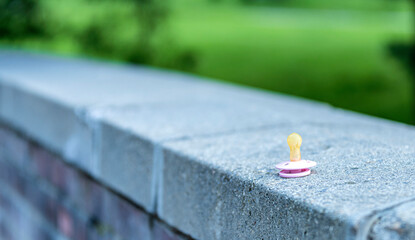 
A baby pacifier is lying on a stone slab outside.