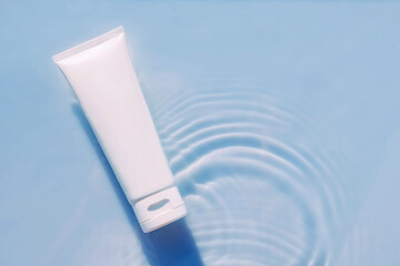 Cosmetic moisturizer with hyaluronic acid, micellar emulsion on blue water background with splashes. Mockup of cosmetic packaging on water background