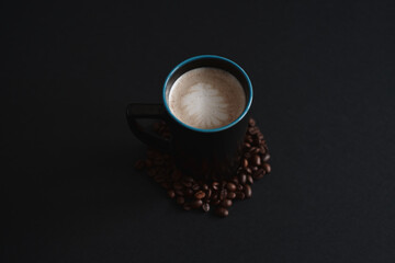 dark cup with creamy coffee on the dark background