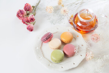 お皿に乗ったたくさんのカラフルなマカロンと紅茶