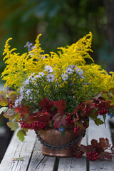 Autumn bouquet of flowers with viburnum berries in a copper planter outdoors