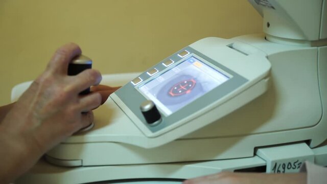Close up of woman doctor working with the refractometer machine. A girl having her eyes tested