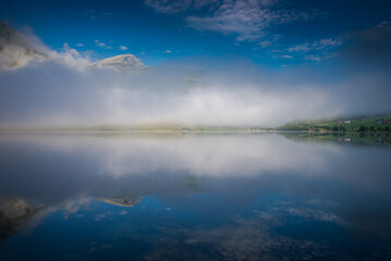 Obraz premium morning fog over the lake. Beautiful nature of Norway, fishing boats on the river