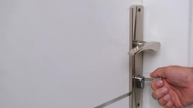 The man opens the door of the room with the key.