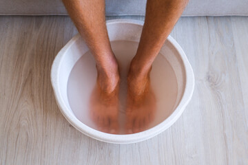 Man made bath with hot water and baking soda for his feet. Homemade bath soak for dry feet skin