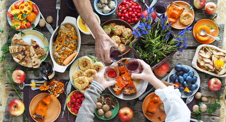 Detail of a set table with blue flowers. Thanksgiving. Healthy rustic natural food. Guest hands over the table.