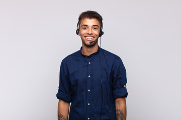 young telemarketer man smiling happily with a hand on hip and confident, positive, proud and friendly attitude - obrazy, fototapety, plakaty