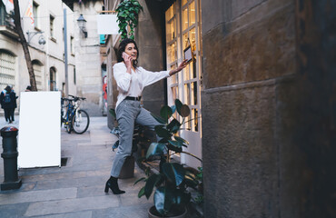 Cheerful female user calling to best friend for discussing shopping time while opening doors to...