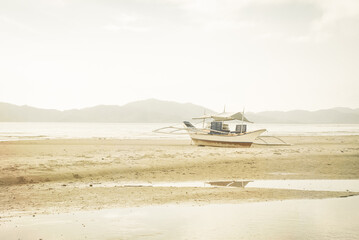 Obraz premium A fishing boat stranded on a beach in low tide on the island of Romblon in the Philippines, South East Asia.