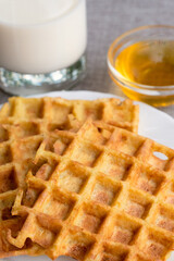 Part of orange waffles with glass of milk.