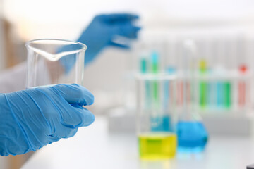 Female chemist holds test tube of glass in his hand overflows a liquid solution of potassium permanganate conducts an analysis reaction takes various versions of reagents using chemical manufacturing.