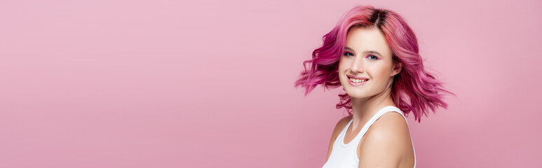 young woman with colorful hair smiling isolated on pink, panoramic shot