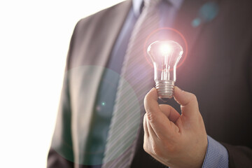 Obraz na płótnie Canvas Innovation Technology New Creative Business Vision. Office Man in Suit Holding Traditional Light Bulb. Executive Manager with Lamp in Hand. Inspiration Symbol. Saving Electric Energy Solution