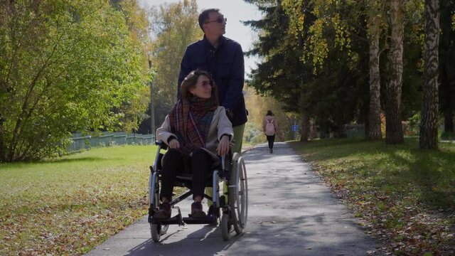 Woman on wheelchair with boyfriend at autumn park