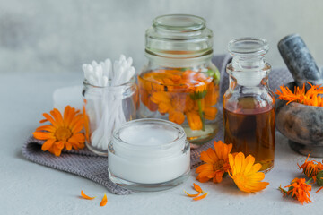 Bottle of pot marigold tincture, with fresh and dry calendula flowers in background. Natural herbal alternative medicine, healing and medicinal herbs.