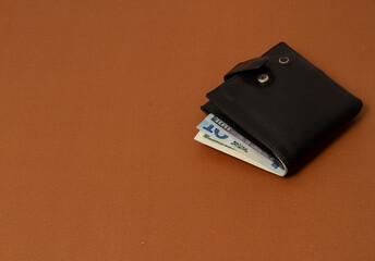 wallet with money, men`s black on a beige background, top view , horizontal