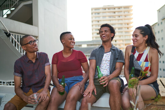 Happy young friends drinking beer on urban rooftop
