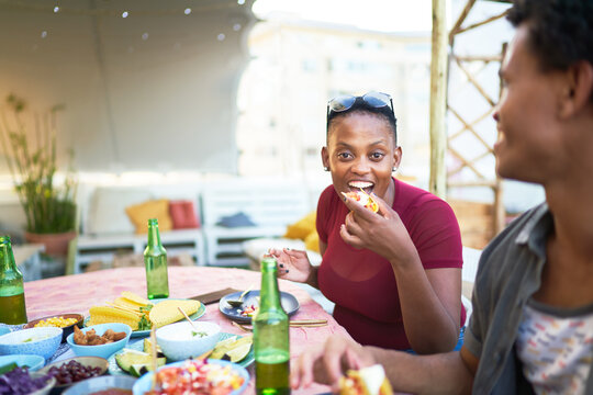 Portrait Happy Young Woman Eating Taco At Patio Table