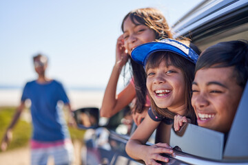 Portrait happy kids leaning out sunny car window