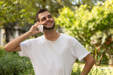 attractive young man with beard talking on mobile phone outdoors