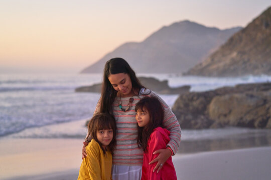 Affectionate mother and daughters hugging on beach