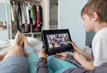 POV family with digital tablet video chatting with friends on bed