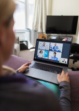 Woman with laptop video chatting with doctors from sofa
