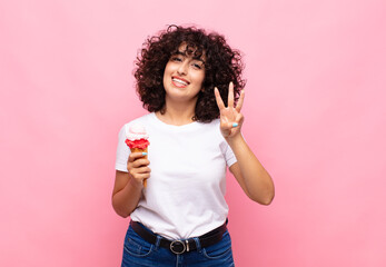 young woman with an ice cream smiling and looking friendly, showing number three or third with hand...