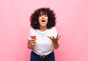 young woman with an ice cream looking angry, annoyed and frustrated screaming wtf or what’s wrong...