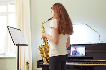 Girl taking online saxophone lesson at home