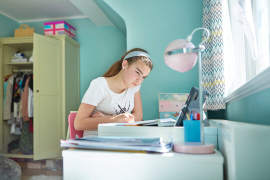 Focused girl homeschooling in bedroom