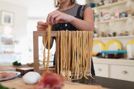 Teenage girl making fresh homemade pasta in kitchen - Powered by Adobe