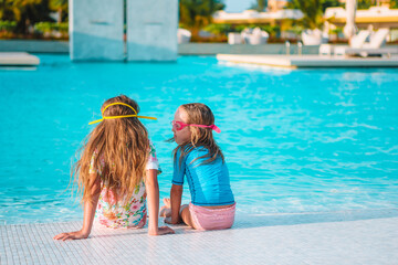 Fototapeta na wymiar Adorable little girls playing in outdoor swimming pool on vacation