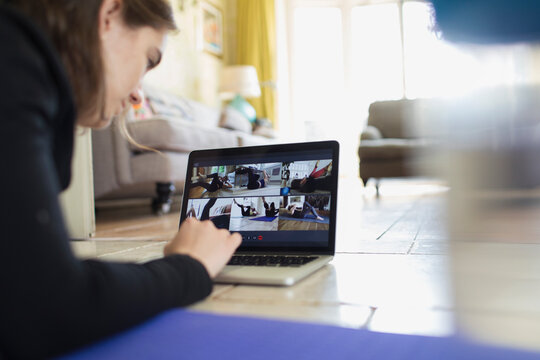 Teenage girl exercising online at laptop screen on floor
