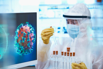 Female scientist in clean suit with test tubes studying coronavirus