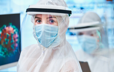 Portrait confident female scientist in clean suit studying coronavirus