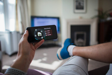 POV Man checking home security on smart phone in living room