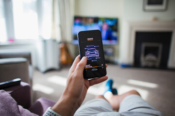 POV Man checking remote car control on smart phone in living room