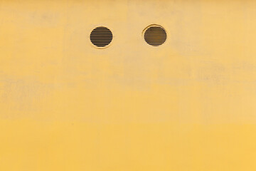 Yellow concrete wall with two round ventilation holes