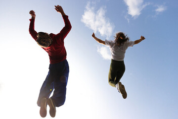 A guy and a girl do a synchronized  backflip against the sky...