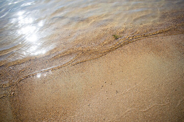 sandy beach with sun reflection on the water