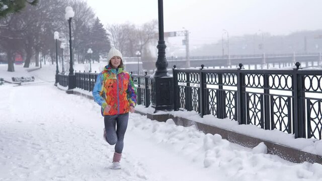 Healthcare, sport concept. Young woman running outdoors in a city park on a cold winter day