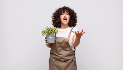 young woman gardener looking angry, annoyed and frustrated screaming wtf or what’s wrong with you