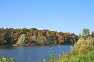Autumn park in September on a bright warm day, a lake with yellow trees. Beautiful bright landscape in the park, seasons, golden autumn season, background, selective focus