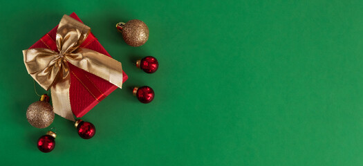 Christmas composition with a gift and Christmas balls on a green background