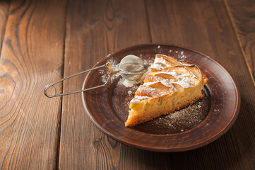A piece of homemade pie on a plate of powdered sugar in a rustic style. Sliced apple pie with icing...