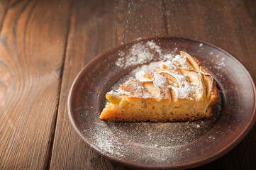 A piece of homemade pie on a plate of powdered sugar in a rustic style. Sliced apple pie with icing...