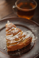 A piece of homemade pie on a plate of powdered sugar in a rustic style. Sliced apple pie with icing close-up and copy space.